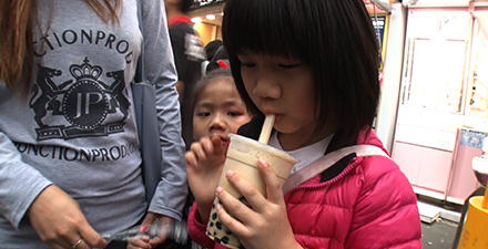 太いストローを使ってタピオカミルクティーを飲む台湾の女の子